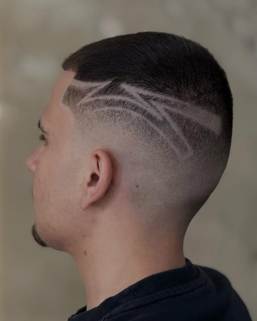 Σχέδιο με ξυράφι σε skin fade, πίσω όψη, στον τσιμεντένιο τοίχο του στούντιο